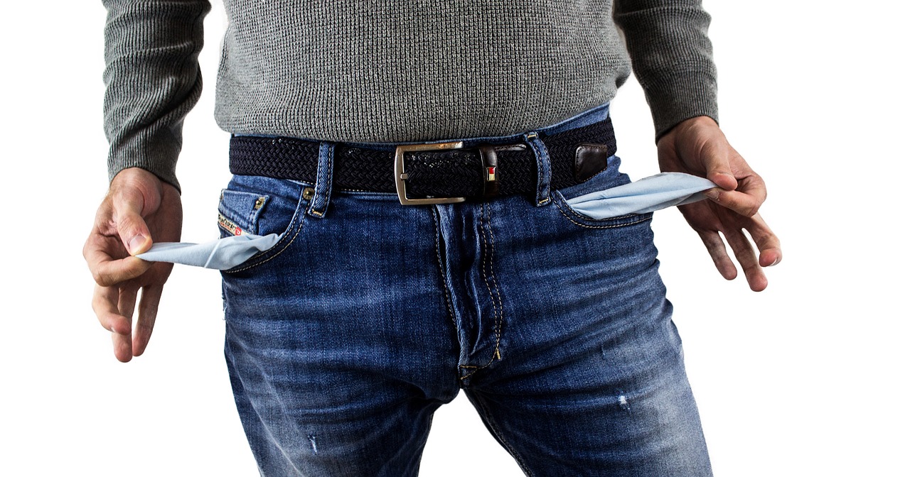 man in blue jeans and grey sweater showing empty pockets