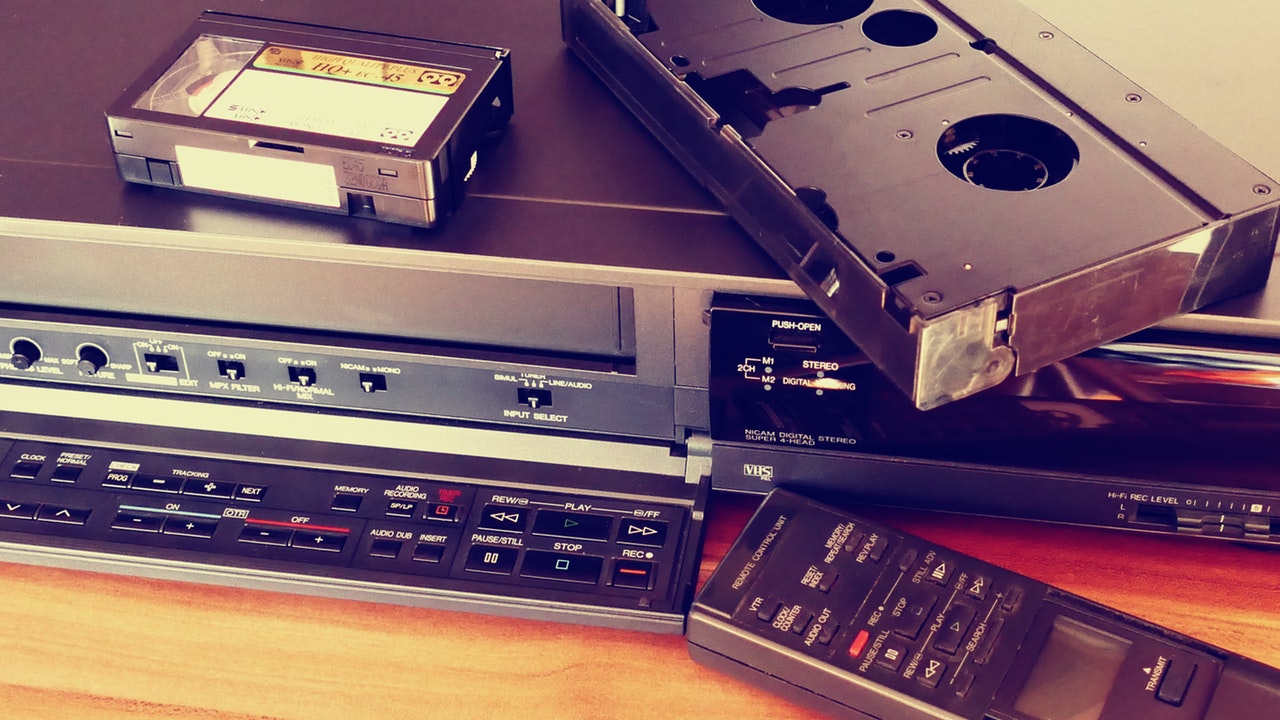 retro vcr showing its control panels, remote controller and two black tapes